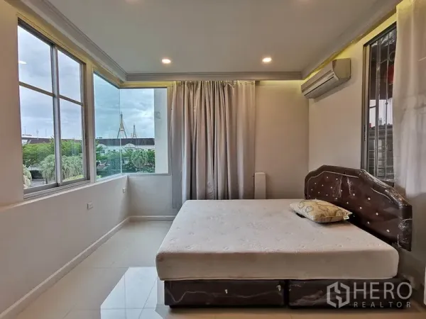 Townhouse for rent or sale in Yan Nawa, Bangkok - Corner bedroom with large windows, city and greenery views, and a wall-mounted air conditioner.