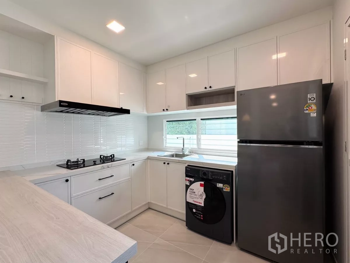独立式住宅 出租在Bang Phli, Samut Prakan - 白色L型厨房，配冰箱与洗衣机，窗边水槽