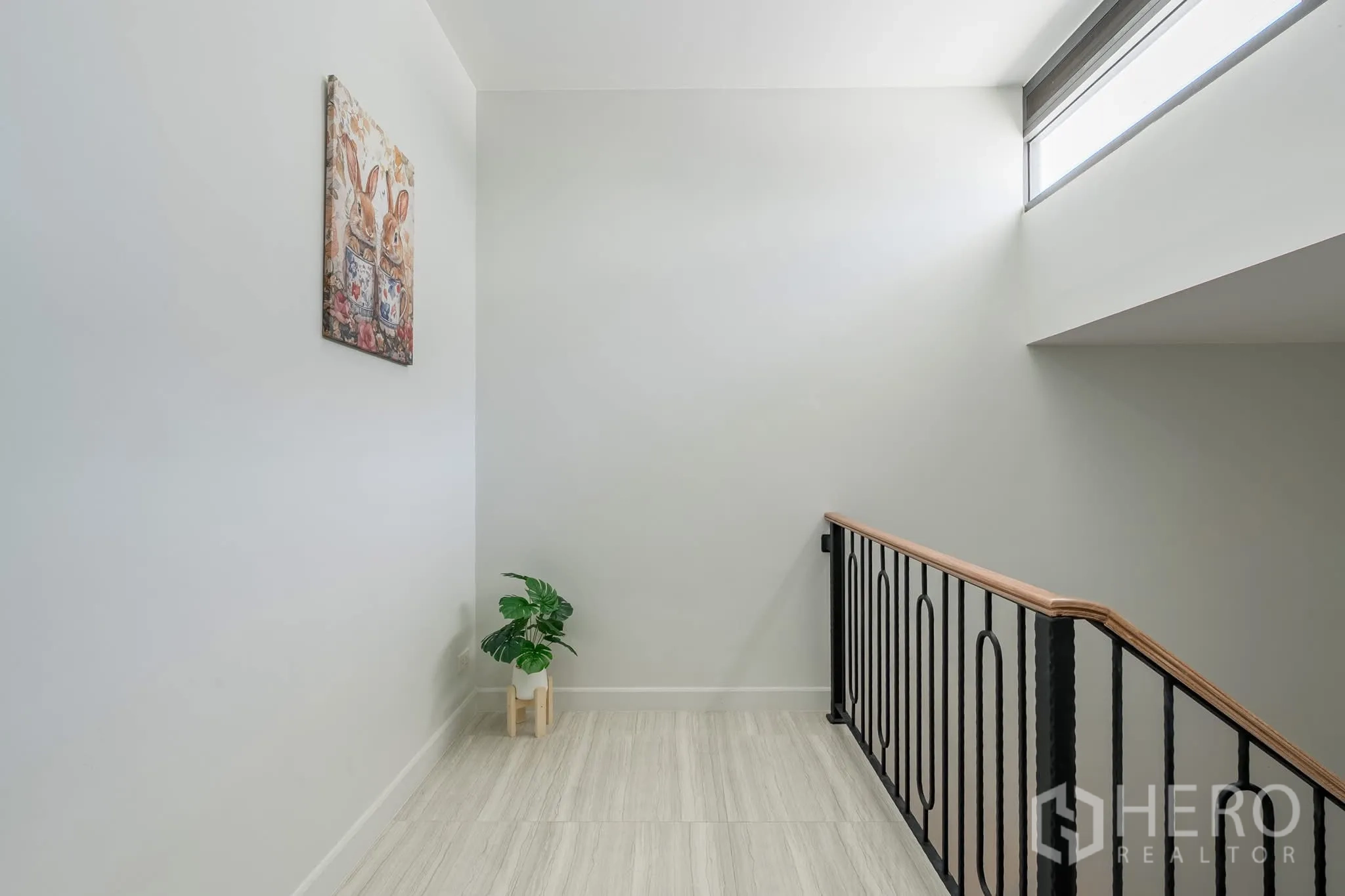 Home Office for rent in Khlong Toei, Bangkok - Upper landing with black metal railing, high window and a small plant.