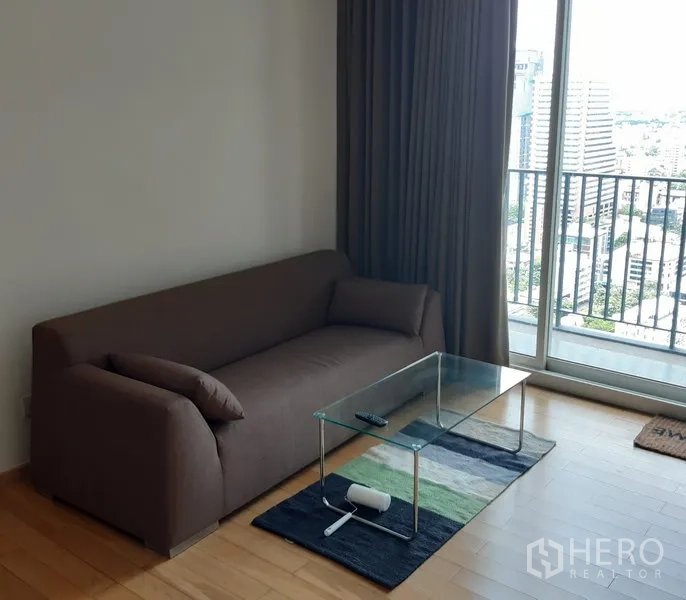 公寓 出售在Khlong Toei, Bangkok - 明亮客厅，棕色沙发与玻璃茶几，连接阳台城市景观。