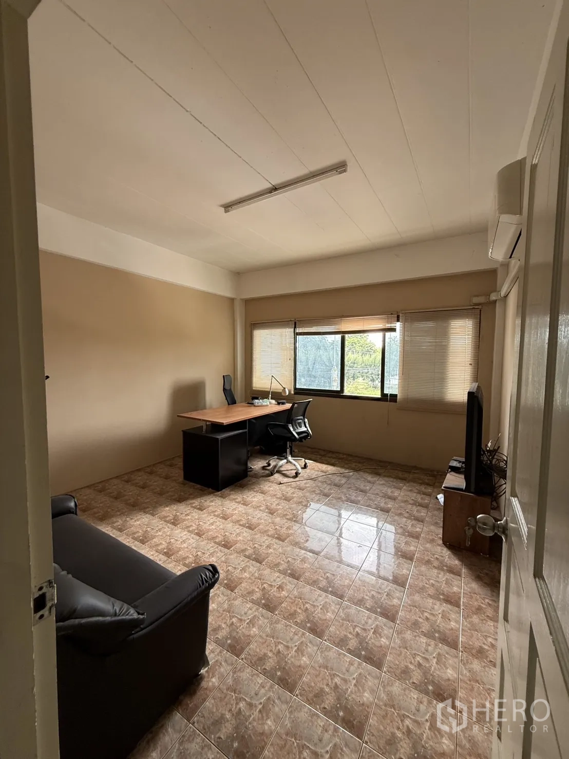 Shophouse for rent in Pak Kret, Nonthaburi - Office room with desk, sofa, large window, and air conditioner.