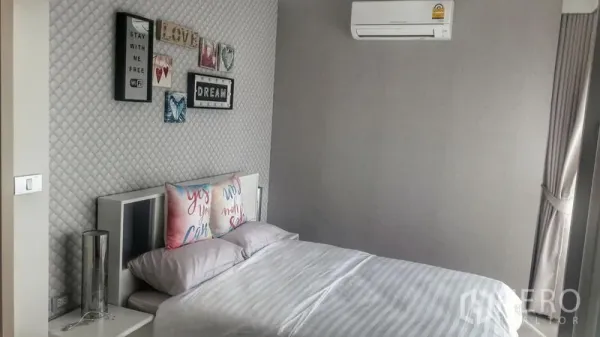 Condominium for rent in Khlong Toei, Bangkok - Bright bedroom with double bed, feature wall, and air conditioner