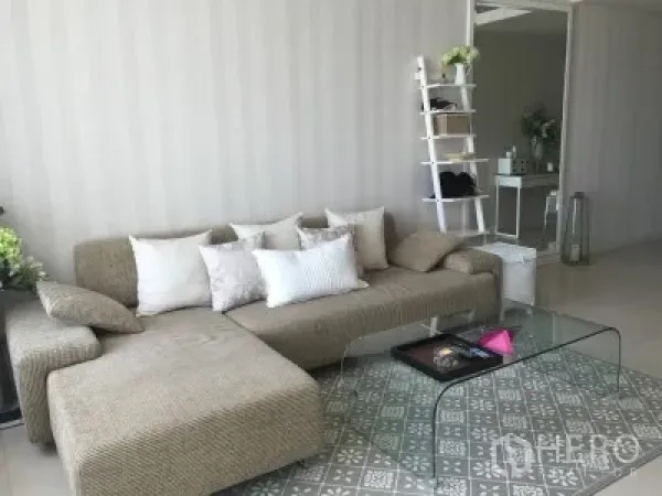 Condominium for rent or sale in Ratchathewi, Bangkok - Bright living room with L-shaped sofa, glass coffee table and patterned rug.