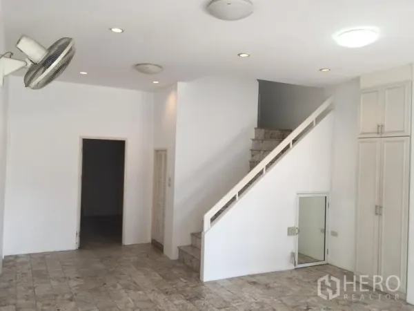 Townhouse for rent in Chatuchak, Bangkok - Bright ground-floor living area with marble-look tile flooring, recessed lights and a staircase to upper levels.