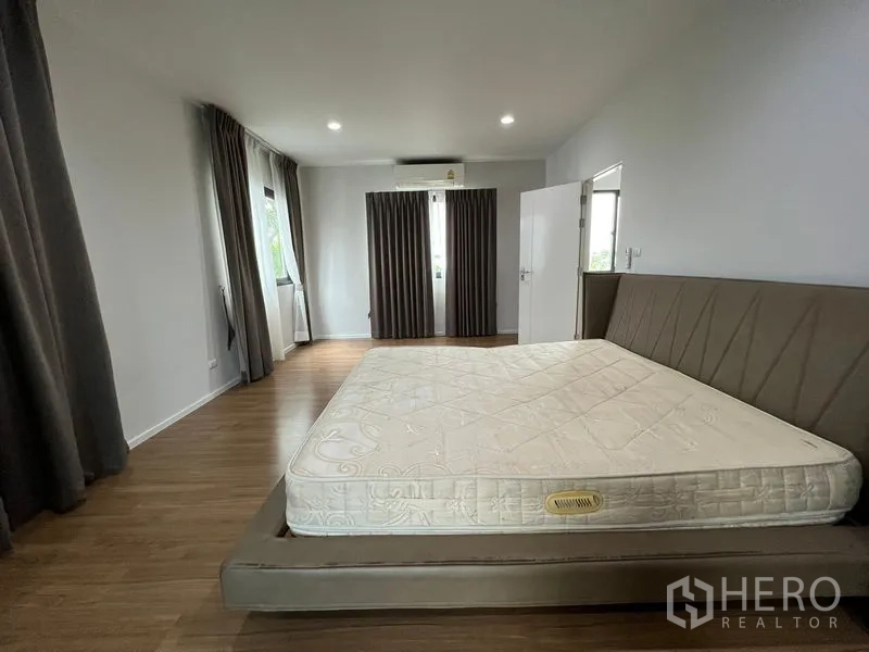 Detached House for rent in Saphan Sung, Bangkok - Large bedroom with platform bed, wooden floors and blackout drapes on multiple windows.
