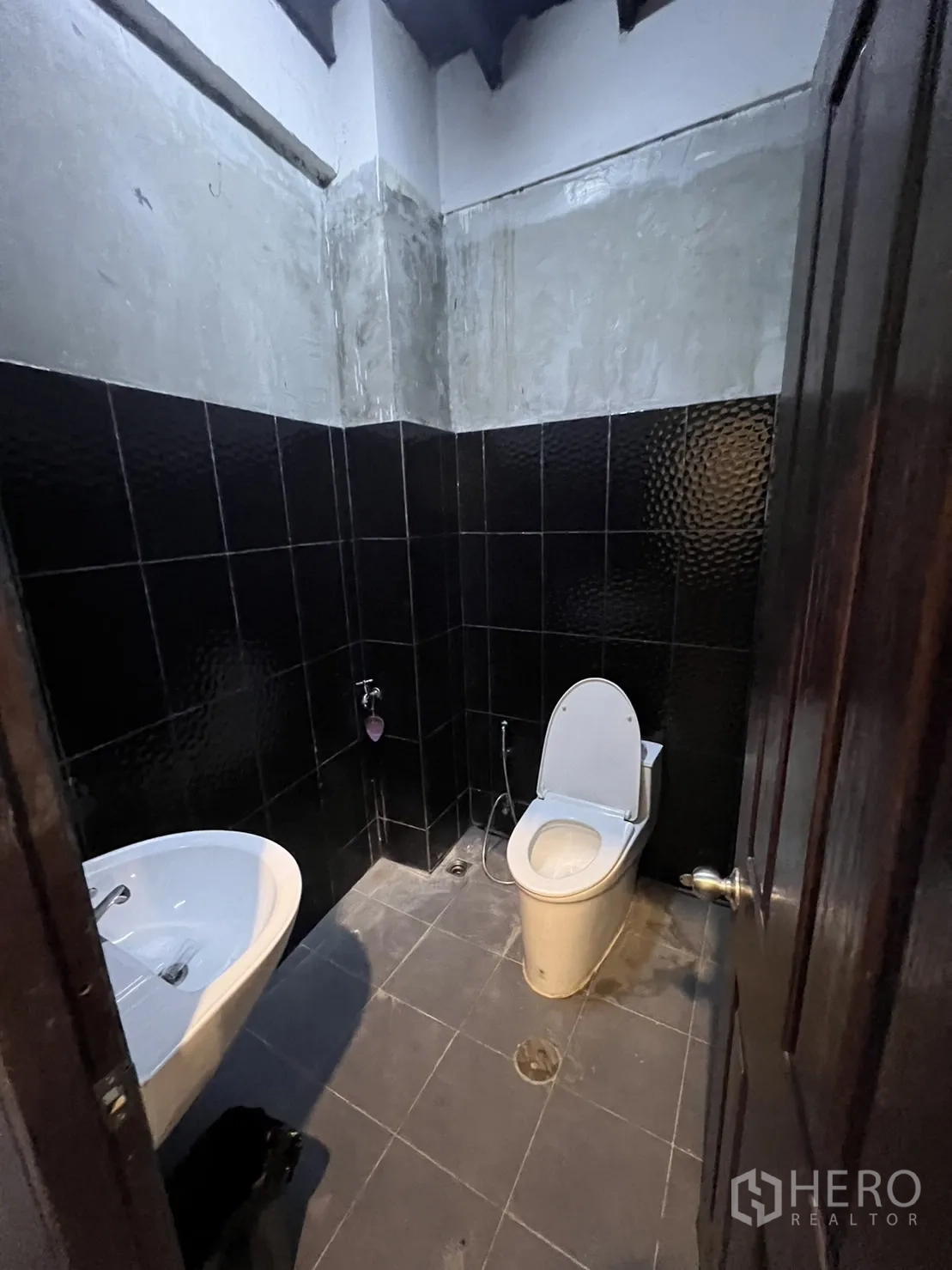 Shophouse for rent in Watthana, Bangkok - Dark-tiled restroom with white basin and toilet.