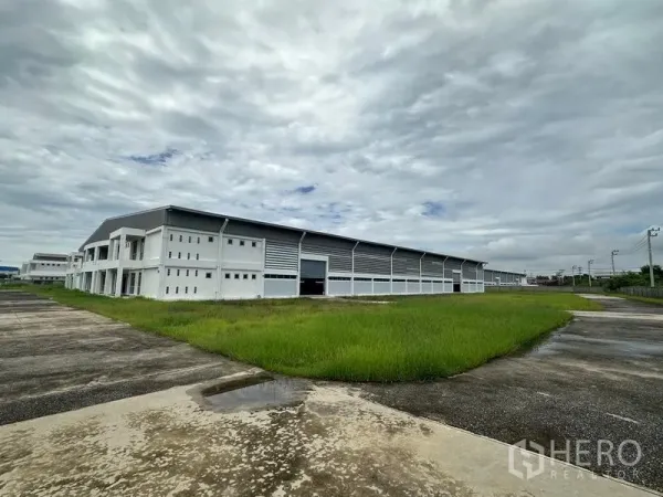 Factory for rent in Pathum Thani - Expansive industrial compound with green verge and loading access.