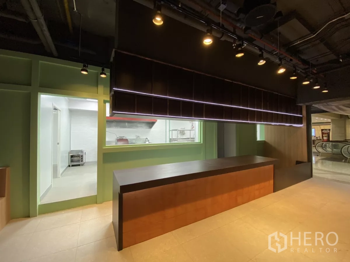 Retail Space for rent - Front counter with hanging shelf by the entrance, kitchen access and escalator visible outside.