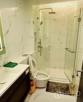 Condominium for rent in Khlong Toei, Bangkok - Bathroom featuring glass shower enclosure, rain shower and modern vanity.