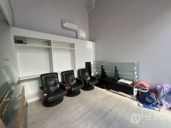 Retail Space for rent - Front retail interior with high ceiling, wall-mounted air conditioner, leather chairs, and glass display counter.