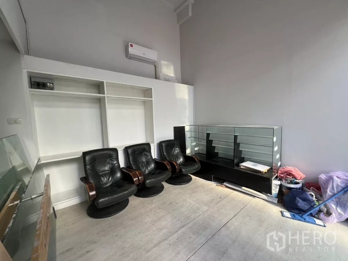Retail Space for rent - Front retail interior with high ceiling, wall-mounted air conditioner, leather chairs, and glass display counter.
