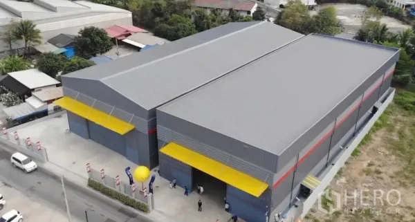 Warehouse for rent in Sai Mai, Bangkok - Aerial view of a twin-bay industrial warehouse complex with yellow canopies and fenced yard in north Bangkok.