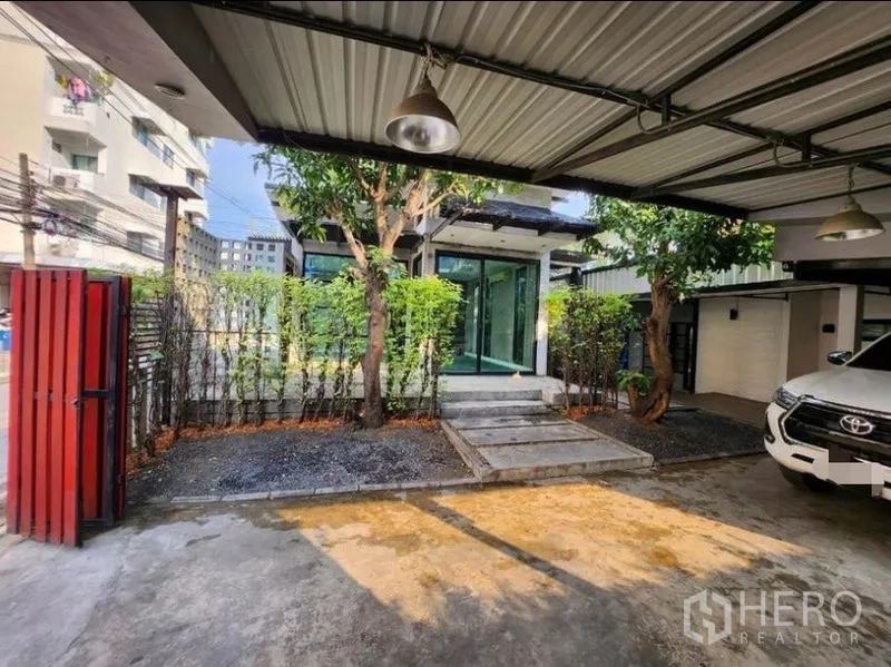 Home Office for rent in Lat Phrao, Bangkok - Covered carport with metal roof, parking for multiple cars, hedge fencing and gate to the property.
