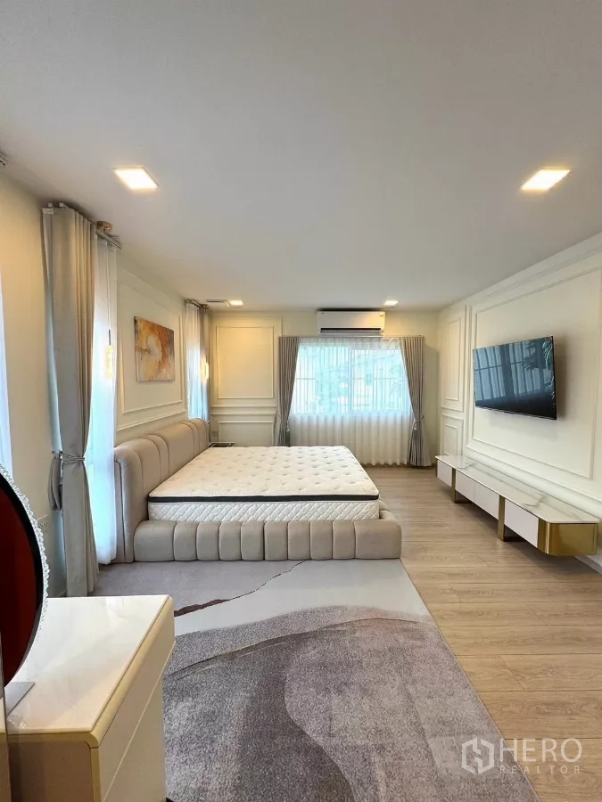 Detached House for rent in Bang Phli, Samut Prakan - Large master bedroom with wall-mounted TV, paneled walls and wood floors.