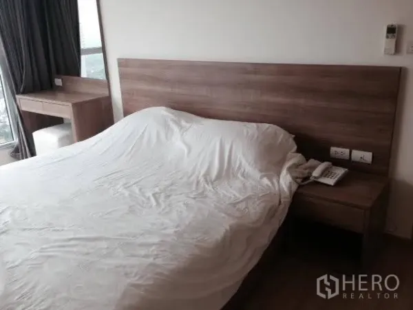 Condominium for rent in Khlong Toei, Bangkok - Master bedroom with wooden headboard, bedside table, desk by the window, and neutral decor.