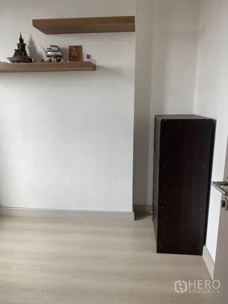 Condominium for sale in Phra Khanong, Bangkok - Minimal corner with floating wooden shelves and a tall storage cabinet