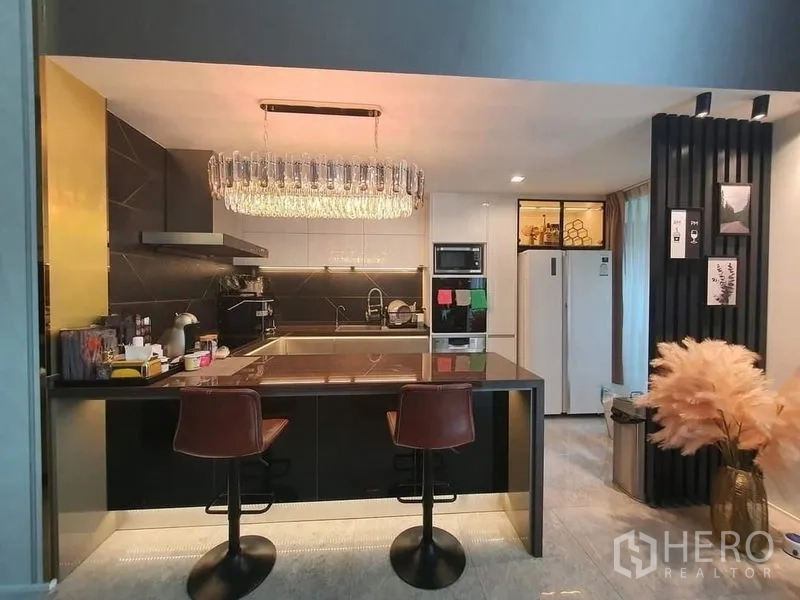联排别墅 出售在Lat Phrao, Bangkok - 现代厨房设中岛吧台与装饰吊灯。