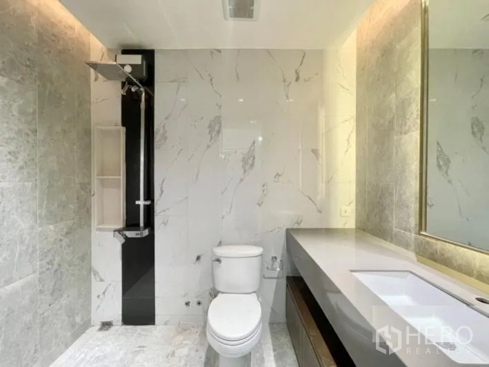 Detached House for rent or sale in Khlong Toei, Bangkok - Modern bathroom with marble tiles, long vanity, backlit mirror and rain shower.