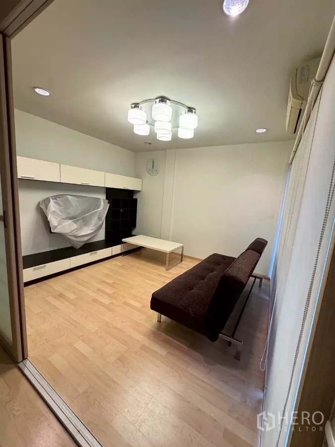 Townhouse for rent in Suan Luang, Bangkok - Family room with sofa bed, wall cabinets and access to balcony.