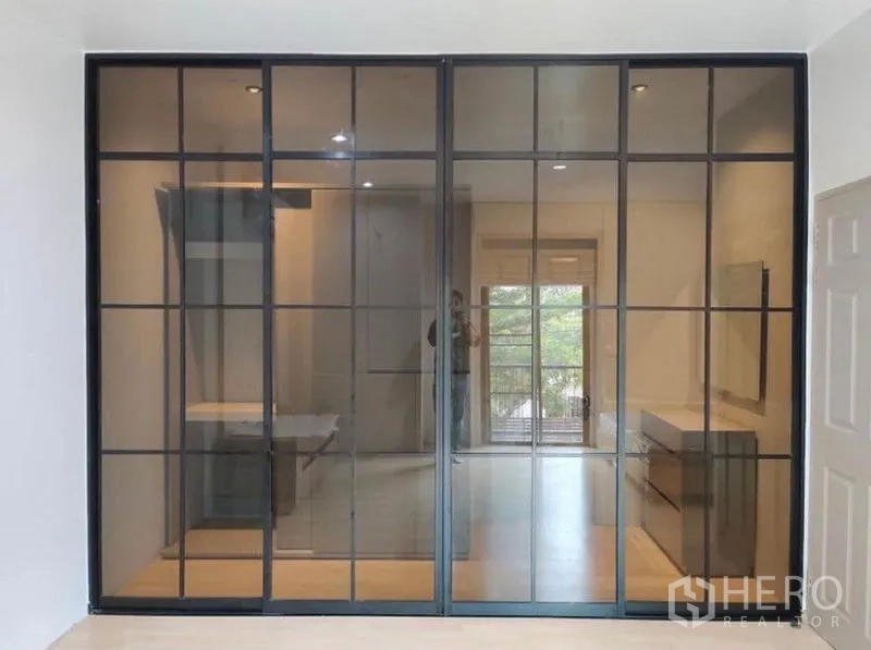 Townhouse for rent in Suan Luang, Bangkok - Full-height framed glass doors revealing the adjoining room and balcony view