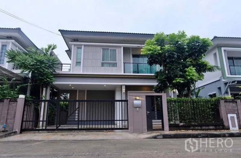 บ้าน ให้เช่าในSuan Luang, Bangkok - ด้านหน้าบ้านสองชั้นพร้อมรั้ว ระเบียง และแนวไม้พุ่มแต่งสวน