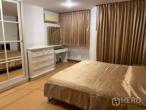 公寓 出租或出售在Watthana, Bangkok - 主卧配金色窗帘、镜面衣柜、五斗橱与化妆桌。