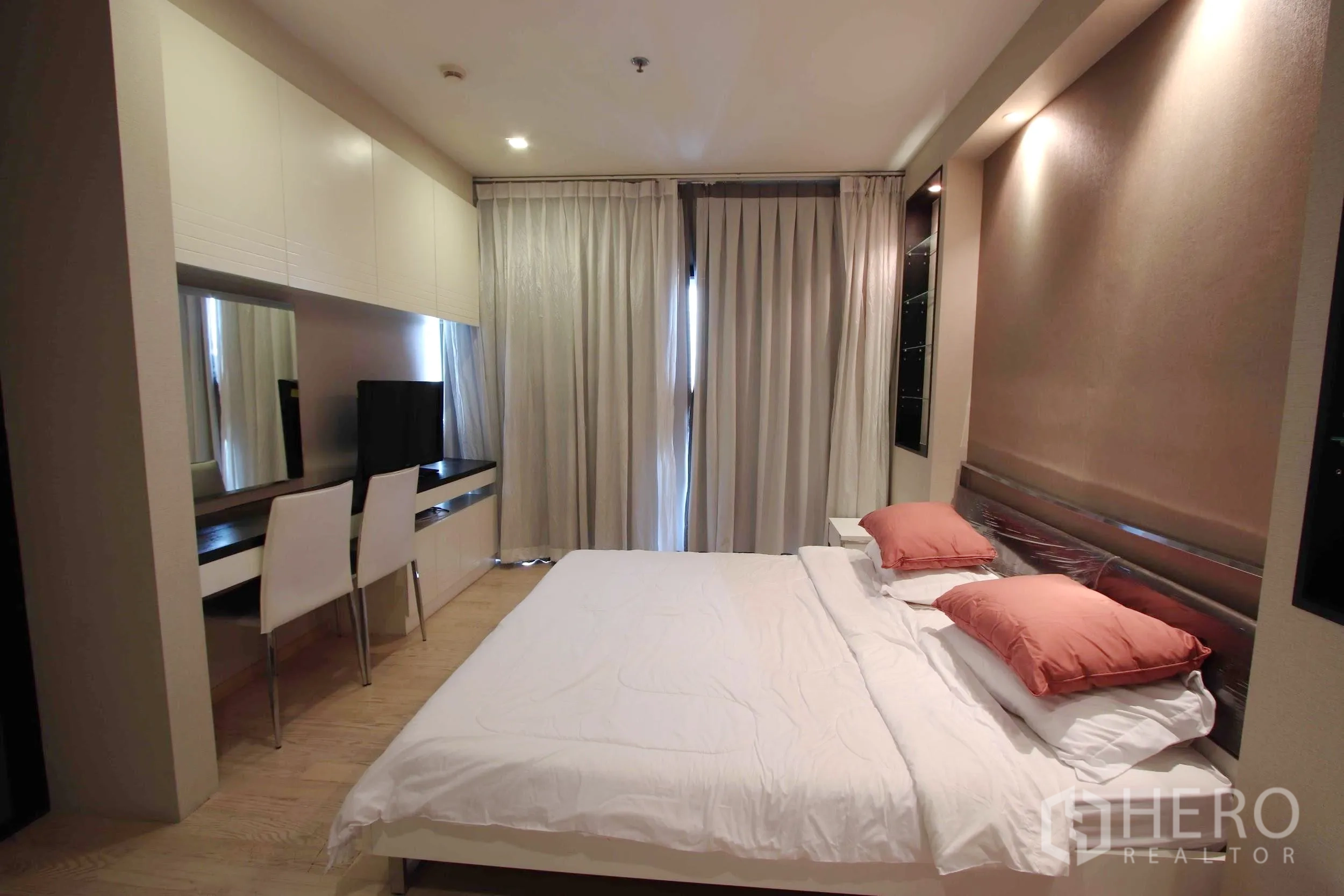 Condominium for rent in Khlong Toei, Bangkok - Master bedroom with king bed, long built-in desk, wardrobes and full-length curtains for privacy.