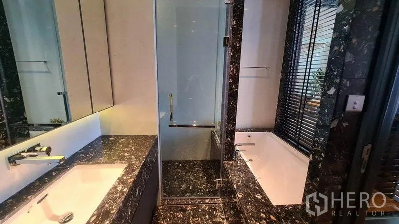 Condominium for rent in Khlong Toei, Bangkok - Luxury bathroom featuring stone countertop, glass shower and bathtub with blinds.