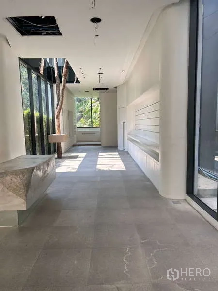 Standalone for rent in Khlong Toei, Bangkok - Bright corridor with floor-to-ceiling windows, floating counter and garden outlook.