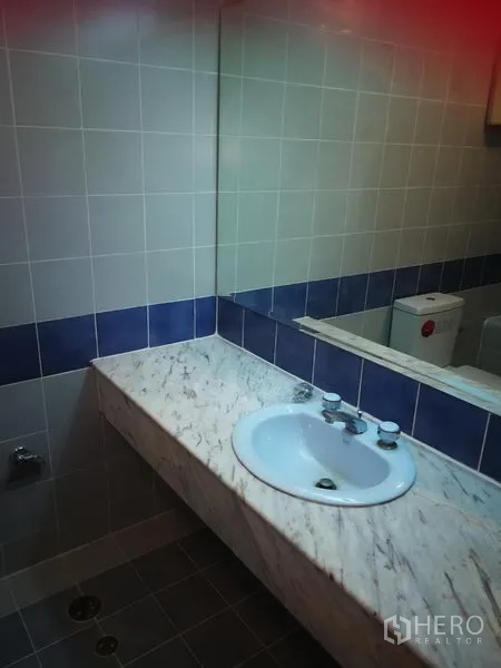 Townhouse for rent or sale in Watthana, Bangkok - Tiled bathroom vanity with marble countertop, sink and large mirror.