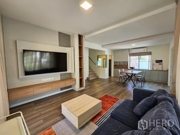 Detached House for rent in Bang Phli, Samut Prakan - Bright open-plan living and dining area with built-in TV wall and wood floors.
