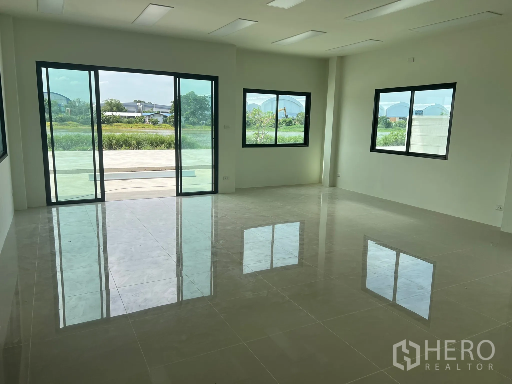 Factory for rent in Bang Phli, Samut Prakan - Bright ground-floor office with glossy tiled floors, sliding glass doors and green views.