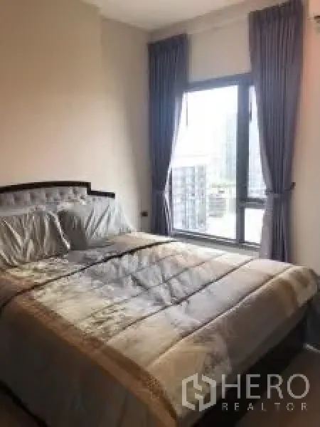 Condominium for rent or sale in Khlong Toei, Bangkok - Cozy bedroom with large window, city view and dark curtains.