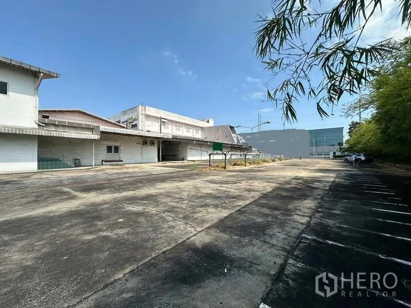 Factory for rent or sale in Thanyaburi, Pathum Thani - Large concrete yard and car park adjoining multiple factory buildings.