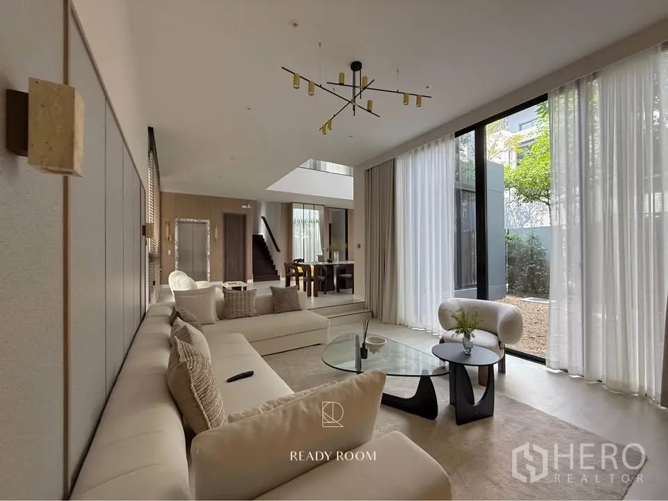 Detached House for rent in Bang Kapi, Bangkok - Open‑plan living area with sectional sofa and full‑height windows for natural light.