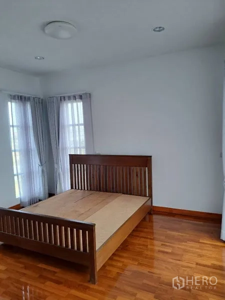 独立式住宅 出租在Prawet, Bangkok - 次卧配木床与两扇窄窗、薄纱窗帘。