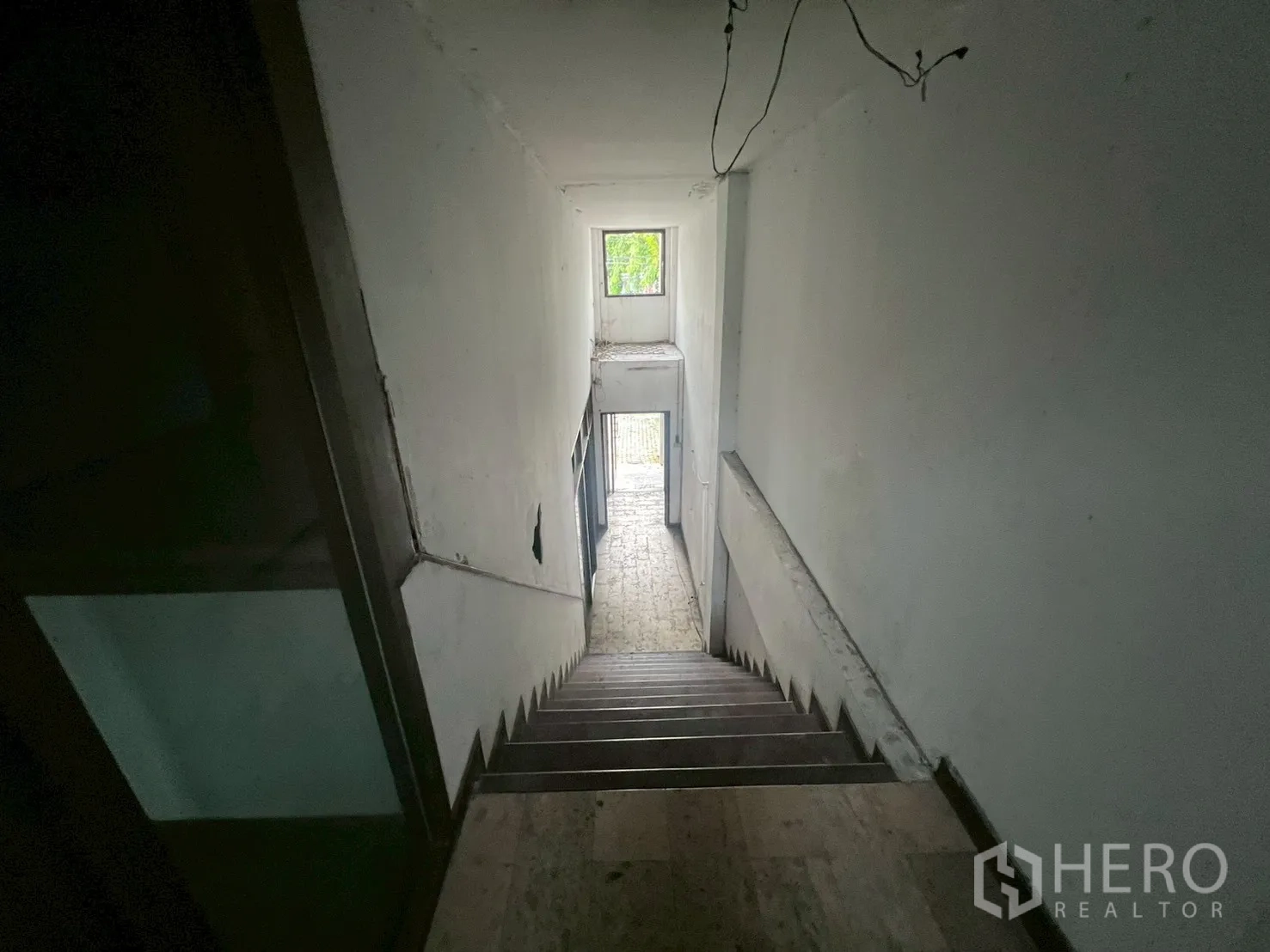 Shophouse for rent in Phra Khanong, Bangkok - Staircase descending to the ground floor lobby with window lighting.