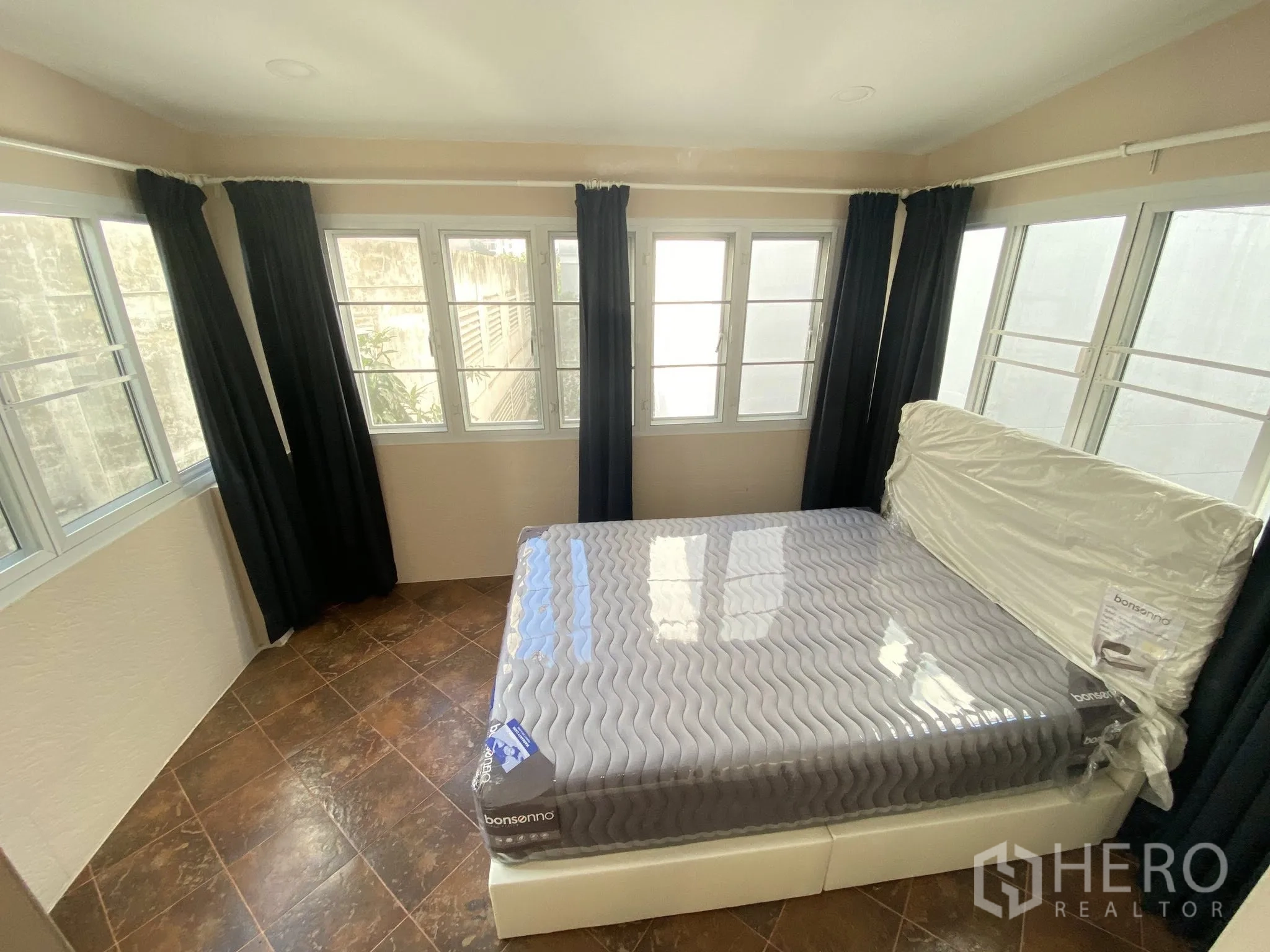 家庭办公室 for rent in Pathum Wan, Bangkok - 转角卧室，四周多扇窗配遮光窗帘，地面为瓷砖。