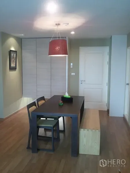 Condominium for rent in Khlong San, Bangkok - Dining area with pendant light, dark wood table and a built-in closet by the entry.