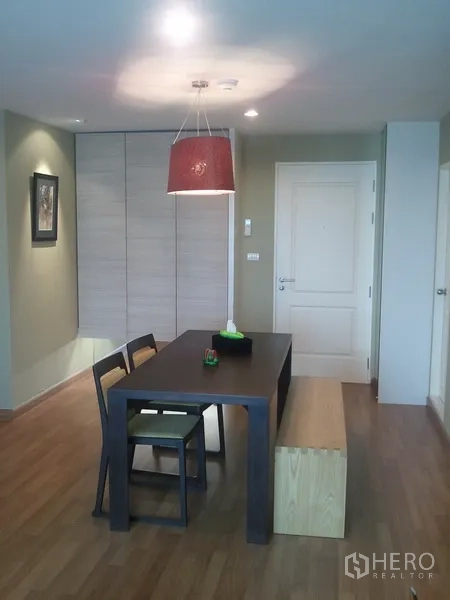 Condominium for rent in Khlong San, Bangkok - Dining area with pendant light, dark wood table and a built-in closet by the entry.