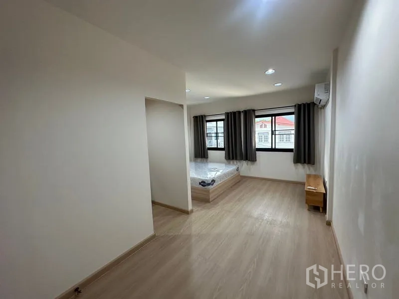 Townhouse for rent or sale in Phra Khanong, Bangkok - Large bedroom with wide windows and light wood flooring.