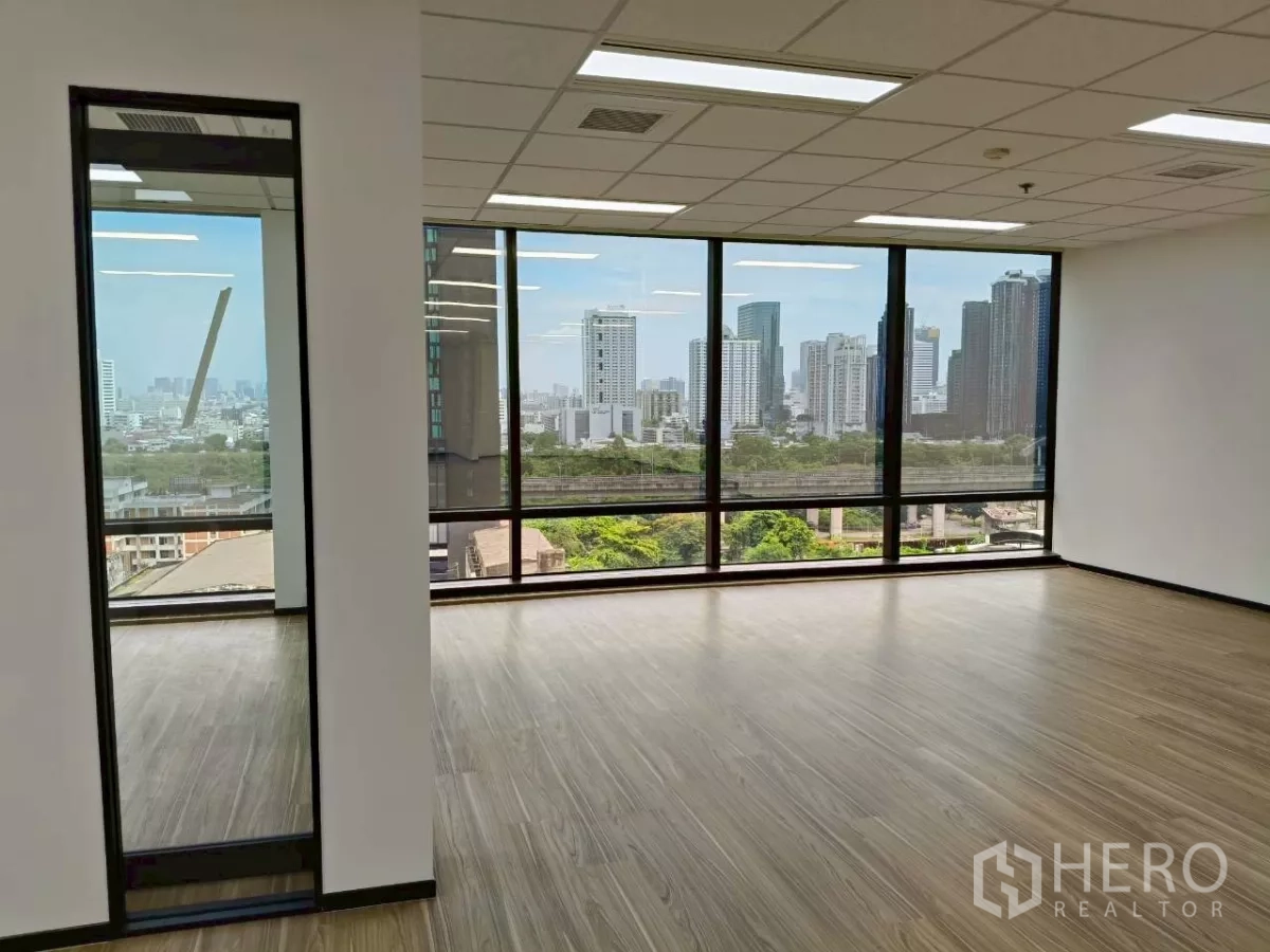 Office Space for rent - Corner office area with full-height windows showcasing greenery and Bangkok’s skyline.