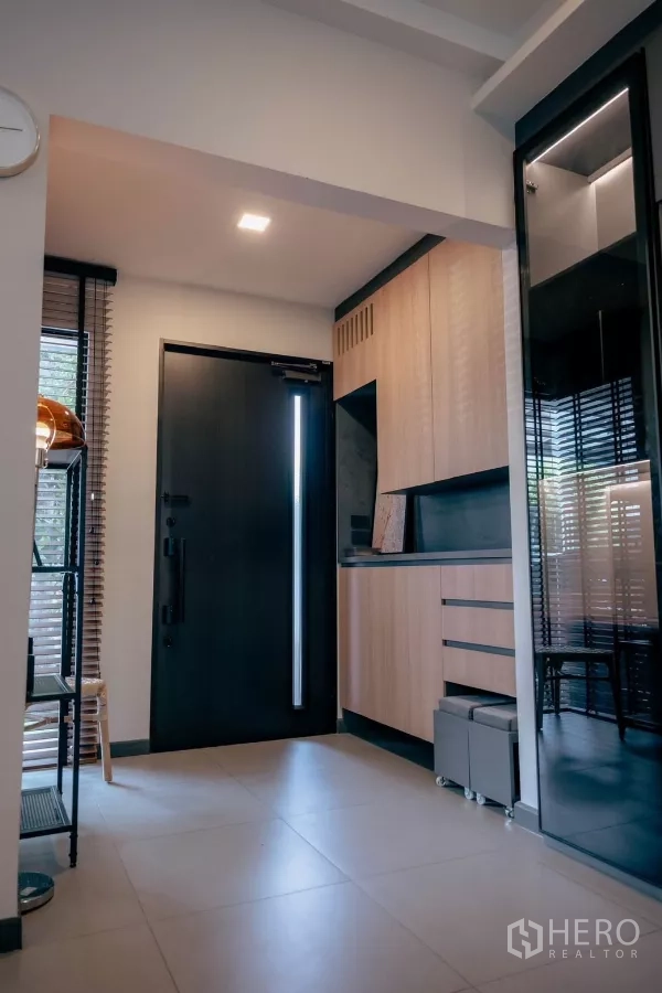 Detached House for rent or sale in Bang Phli, Samut Prakan - Foyer view showing built‑in light wood cabinetry beside the black entry door.