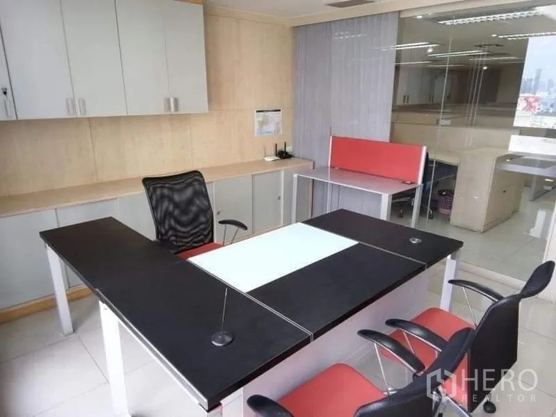 Office Space for rent - Executive office with U-shaped desk, red-and-black chairs and built-in storage beside a glass wall.