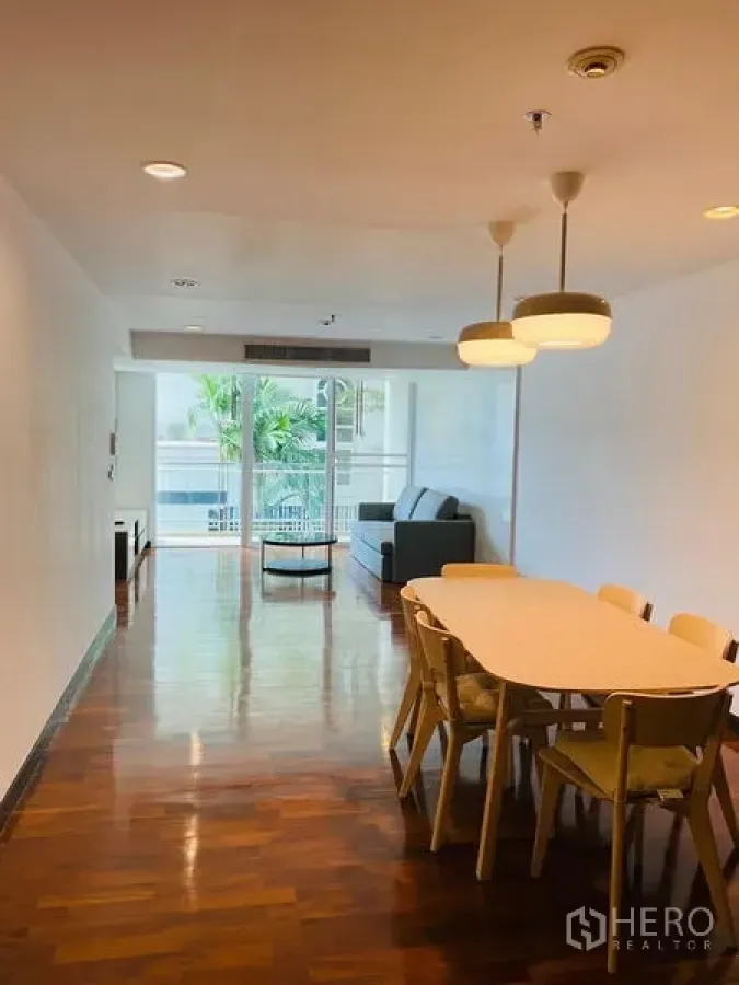 公寓 出租在Watthana, Bangkok - 开放式餐客厅，木地板与吊灯，落地推拉门通向阳台。