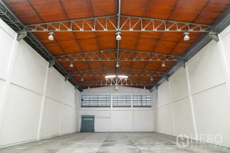 Factory for rent in Bang Sao Thong, Samut Prakan - Bright warehouse hall with ventilated rear wall and overhead lights.