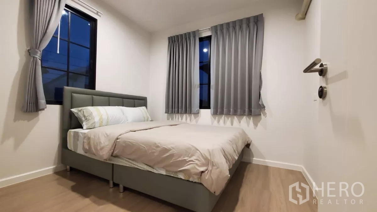 Detached House for rent in Lat Krabang, Bangkok - Guest bedroom with double bed, grey curtains and two corner windows at night.