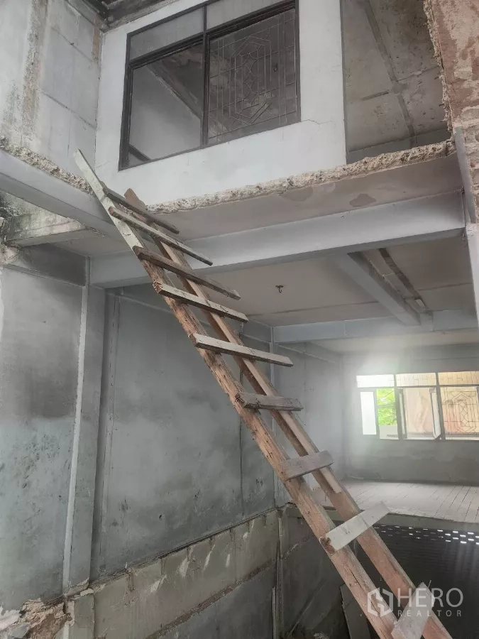 Shophouse for rent in Watthana, Bangkok - Temporary wooden ladder leading to a mezzanine level in an unfinished room.