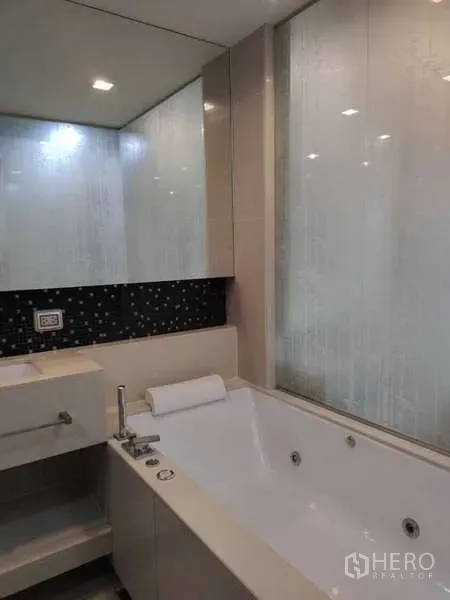 Condominium for rent in Bang Rak, Bangkok - Modern bathroom with large soaking tub and mirrored wall.
