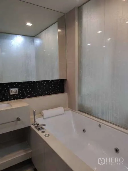 Condominium for rent in Bang Rak, Bangkok - Modern bathroom with large soaking tub and mirrored wall.